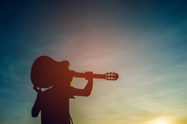 silhouette d’un guitariste dans l’ombre à la lumière du coucher du soleil, concept de silhouette. - men artist guitarist guitar photos et images de collection