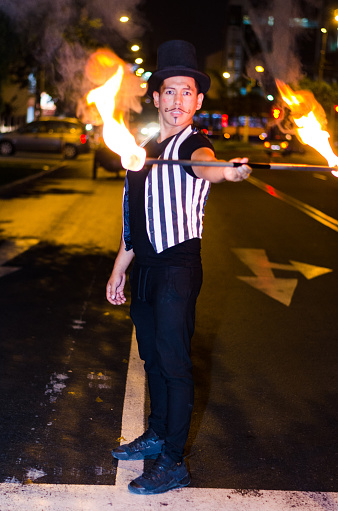 A street artist who makes a show in Lima - Peru, juggling a stick with fire at traffic lights stops, in front of stopped cars