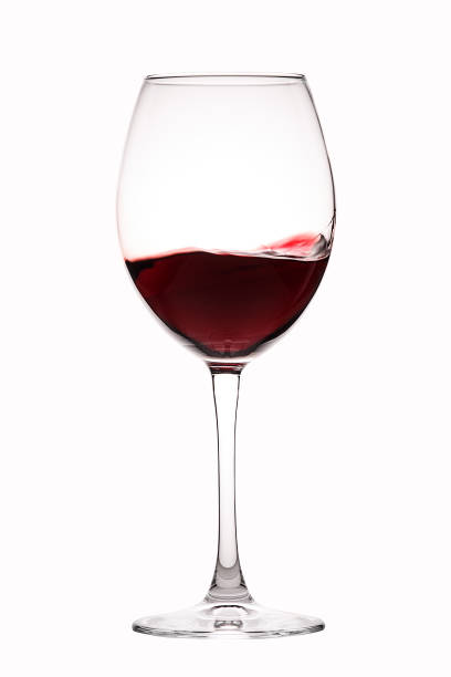 istock Red wine splashing into a glass on an isolated white background. 1141607048