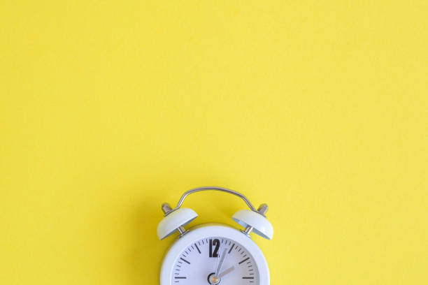 istock Flat lay of small alarm clock on yellow background 1141610121