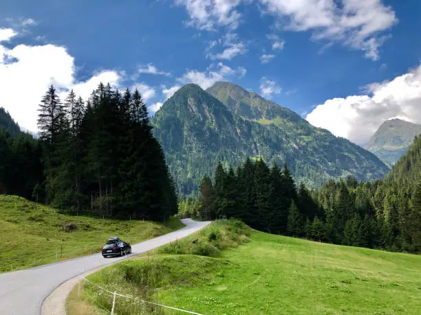 A car driving through beautiful road with big mountains on Neustift im Stubaital road in Austria