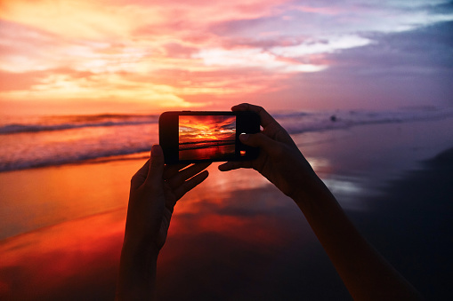 Girl takes a sunset photo on the phone.