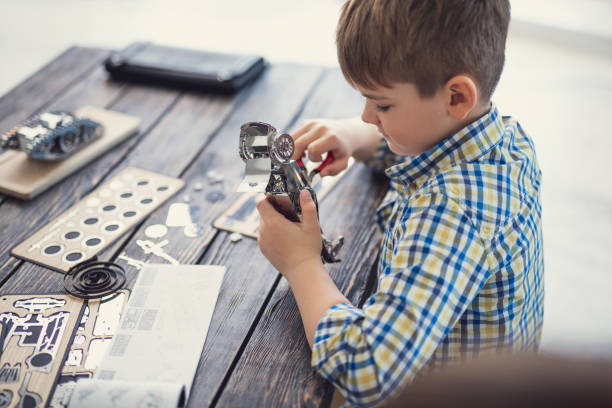 istock Concentrated boy sitting alone and making metal car model 1141613691