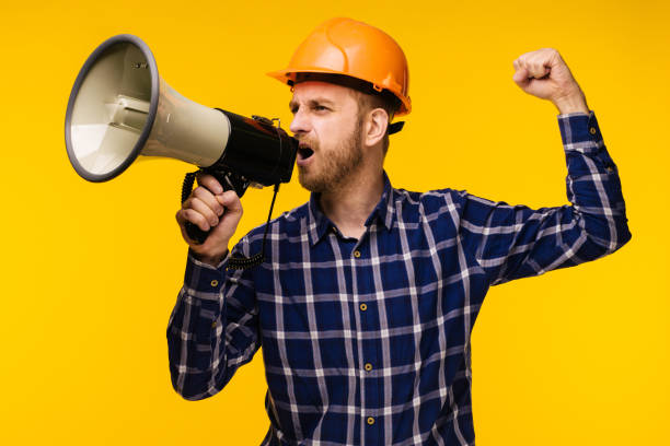 istock Angry worker man with a megaphone on yellow background 1141613994