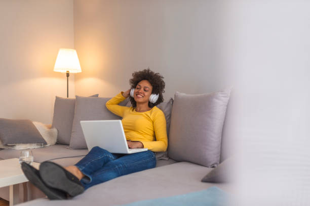 beautiful smiling female student using online education service - lying down women laptop freedom imagens e fotografias de stock