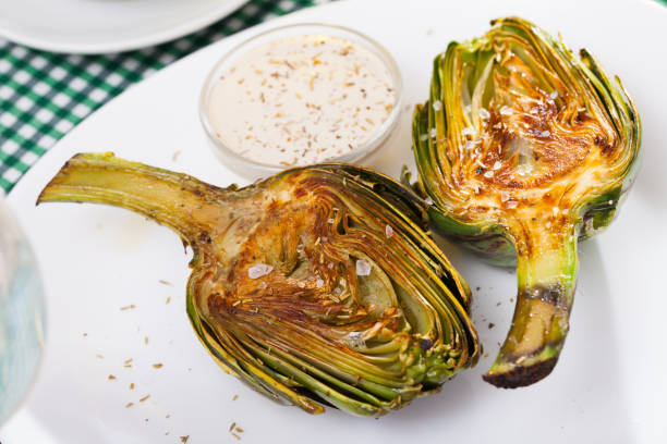 Artichokes served with coarse salt Delicious roasted  halves of artichokes served with coarse salt  on plate artichoke stock pictures, royalty-free photos & images