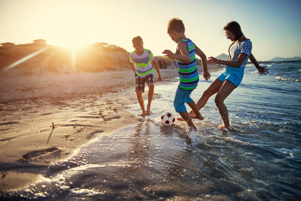 kids playing soccer on on beach - beach football imagens e fotografias de stock