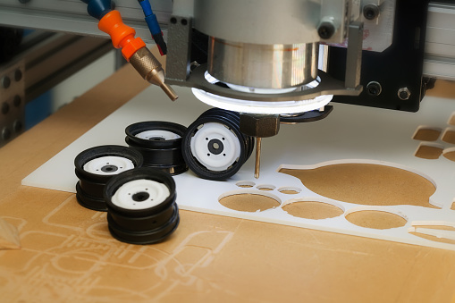 CNC desktop router machine with drill bit used to create prototype wheel designs using ABS plastic.