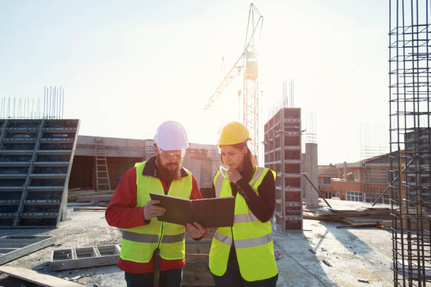 istock Teamwork on construction site working on building construction, Woman architect and man on middle age working together on construction site 1141621635