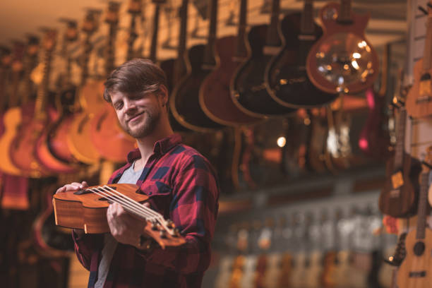 istock Smiling musician with a ukulele indoors 1141622721