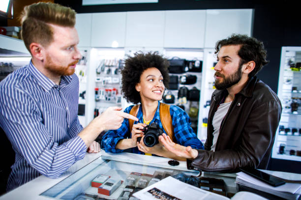 istock Store salesman teaching interested customers some camera tricks on a DSLR camera in a camera accessories store 1141622994