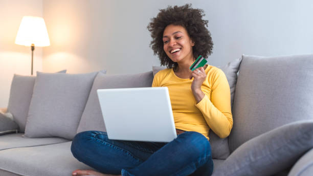 happy woman doing online shopping at home - lying down women laptop freedom imagens e fotografias de stock
