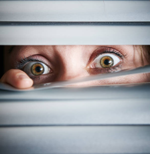 istock Frightened looking female eye peeps through white venetian blind 1141624985