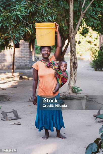 African Mother With Baby Son And Water Bin At Home Stock Photo - Download Image Now - Africa, Malawi, Water