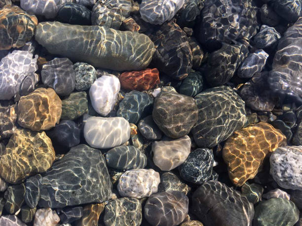 istock Pebbles under water shimmering sunlight, top view. 1141636772