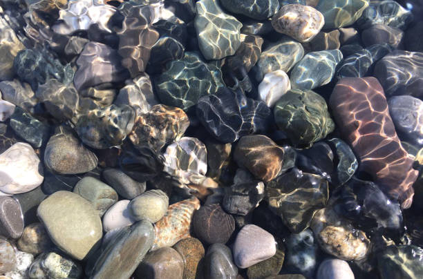 istock Pebbles under water shimmering sunlight, top view. 1141636784