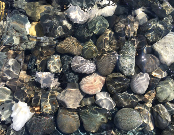 istock Pebbles under water shimmering sunlight, top view. 1141636803