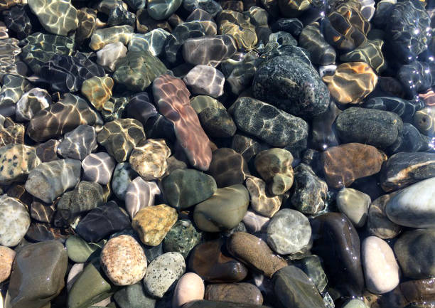 istock Pebbles under water shimmering sunlight, top view. 1141636807