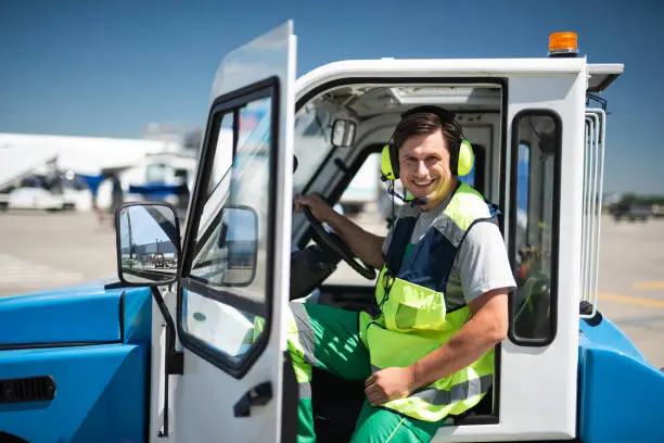 Photo of Smiling airport worker sitting in vehicle