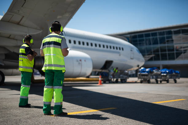 Airport workers looking at modern aircraft Waiting for the flight. Full length portrait of aviation crewmembers. Passenger airplane and trolleys with luggage on background crew stock pictures, royalty-free photos & images
