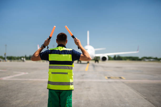 istock Airport worker looking at passenger plane and signaling 1141641177