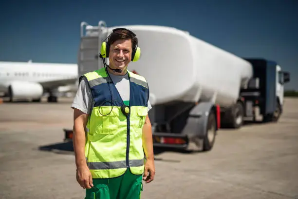 Photo of Laughing airport worker with truck on blurred background