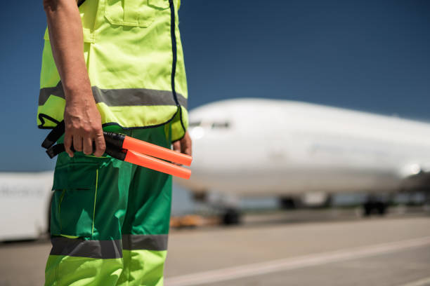 istock Airport worker standing at airdrome with signal wands 1141641204