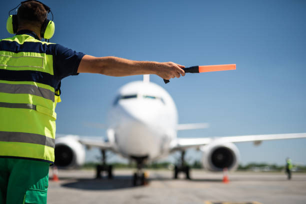 istock Aviation marshall in headphones directing passenger plane 1141641210