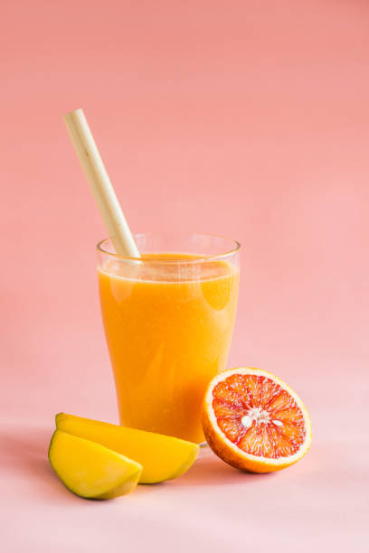 istock Mango and orange smoothie in glass on pink background. 1141641509