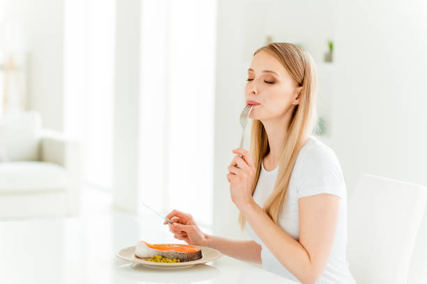 retrato de dama positiva alegre sentirse satisfecho deleite cenar con proteínas vitaminas lamer tenedor cuchillo asiento de la mesa de la cocina llevar ropa moderna de moda moderno - seafood salmon ready to eat prepared fish fotografías e imágenes de stock