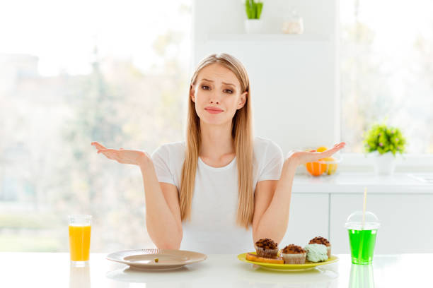 istock Portrait disappointed negative teenager problem choose decision confectionery beverage cupcake muffin junk baked products lunch sit table dressed trendy beautiful casual style outfit big kitchen 1141642673