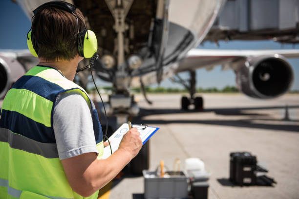 Airport worker looking at passenger plane and writing information Focusing on work. Back view of ground crew member noting data on clipboard while checking aircraft before the flight airplane maintenance stock pictures, royalty-free photos & images