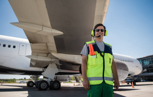istock Cheerful airport worker posing near passenger plane 1141642766