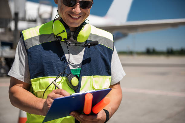 istock Cheerful airport worker looking at clipboard and writing information 1141642783
