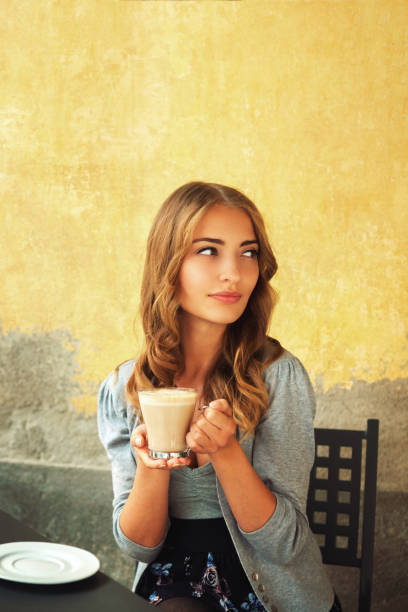 istock Young woman drinking coffee in a sidewalk cafe 1141642913