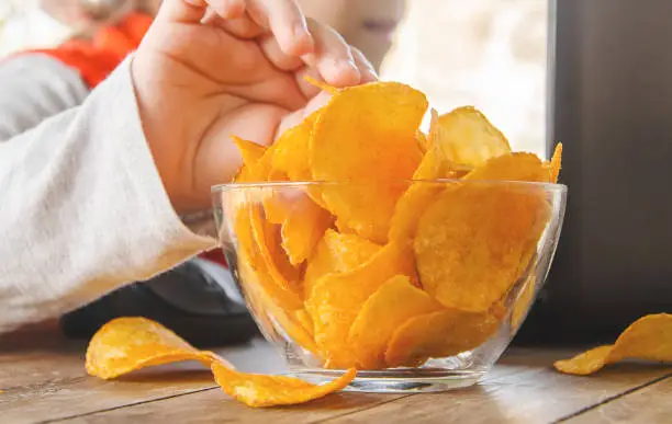 Photo of child with chips behind a computer. selective focus.