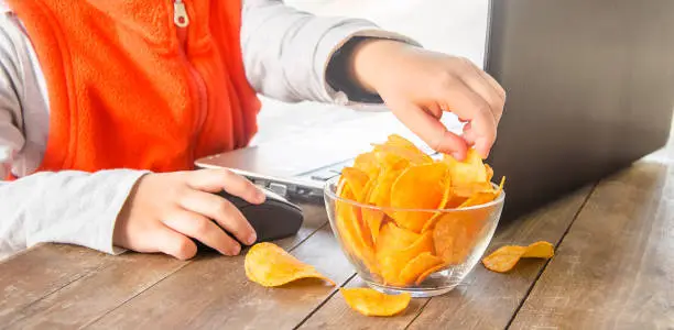 Photo of child with chips behind a computer. selective focus.