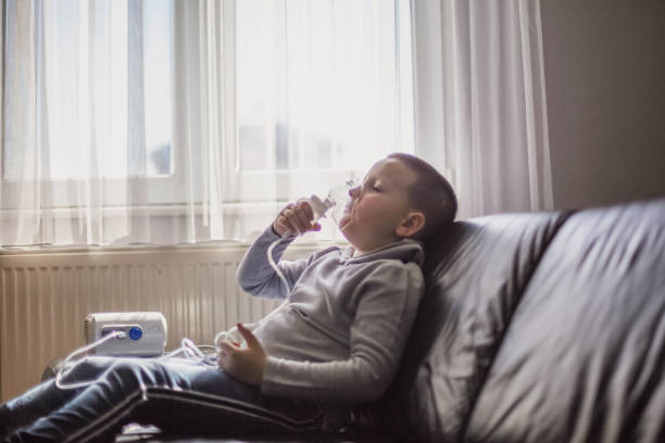 Child using inhaler at home Young boy using inhaler at home respiratory disease stock pictures, royalty-free photos & images