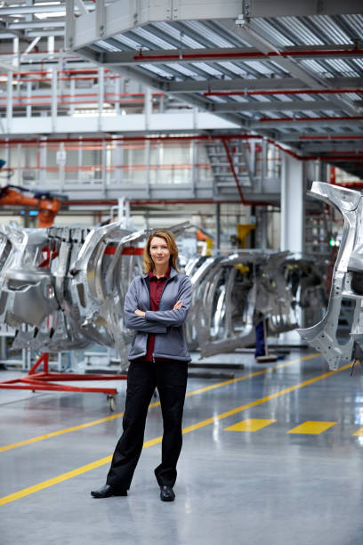 engineer with arms crossed against car chassis - automobile industry transportation indoors vertical imagens e fotografias de stock