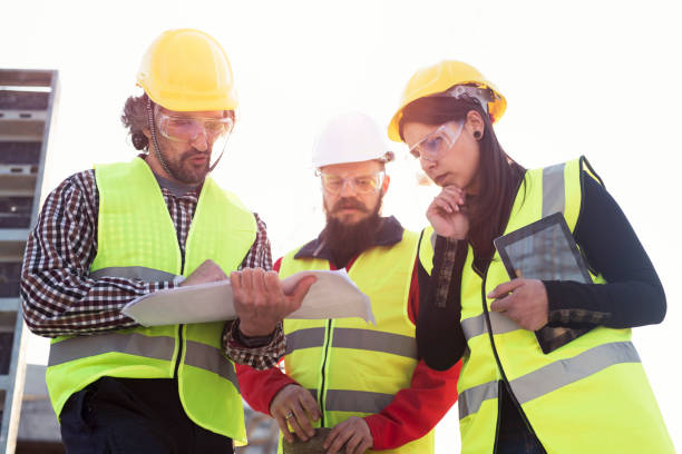 istock Whats not correct? Young woman architect talking with construction workers and looking blueprints. 1141649574