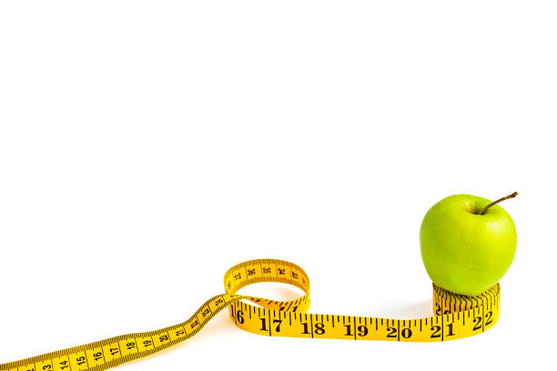 istock Green apple and measuring tape  with centimeters and inches 1141651960