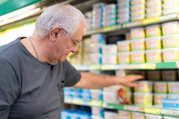 uomo anziano che fa la spesa di burro al supermercato - focus on foreground selective focus focus household equipment foto e immagini stock