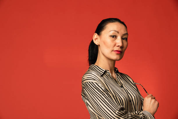 A Focused Female One woman standing in a studio, looking at the camera with a focused, empowered stance. portrait power pose stock pictures, royalty-free photos & images