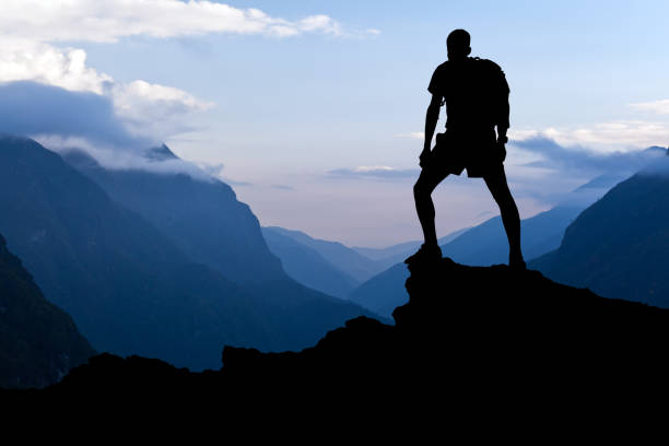 Man hiking success silhouette in mountains stock photo