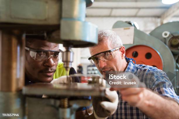 Instructor Guiding Trainee In Using Yoke Machine Stock Photo - Download Image Now - Factory, Instructor, Trainee