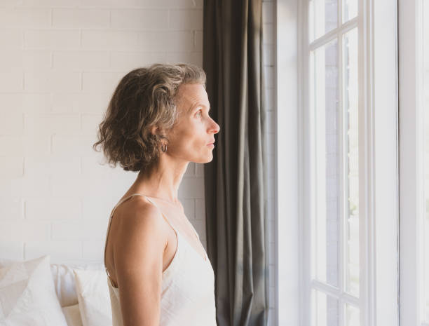 Middle aged woman looking out bedroom window