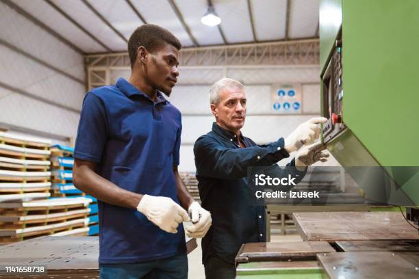 Instructor Teaching Male Trainee In Factory Stock Photo - Download Image Now - Industry, Latin American and Hispanic Ethnicity, 25-29 Years