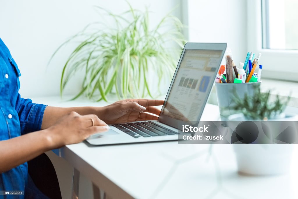 Midsection of pregnant businesswoman using laptop Midsection of pregnant businesswoman using laptop in office. Female executive is working at desk. She is planning new business strategies. Plant Stock Photo