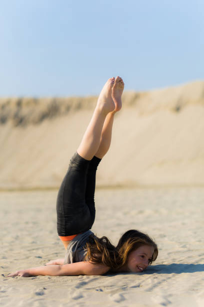 Girl practicing yoga outdoors on the sand