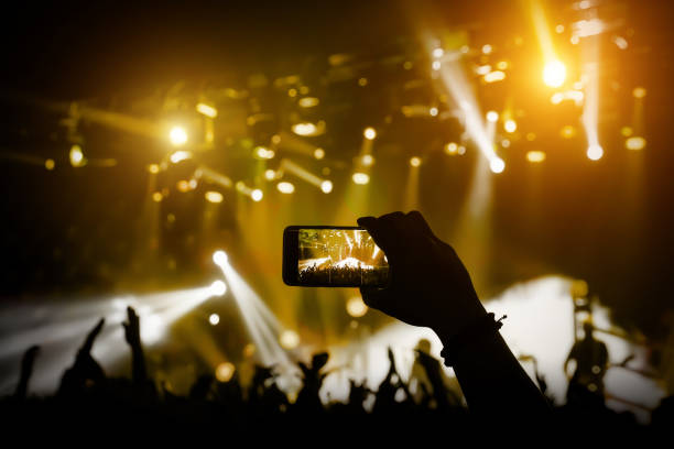 istock Filming a concert on mobile phone camera, yellow light 1141666298